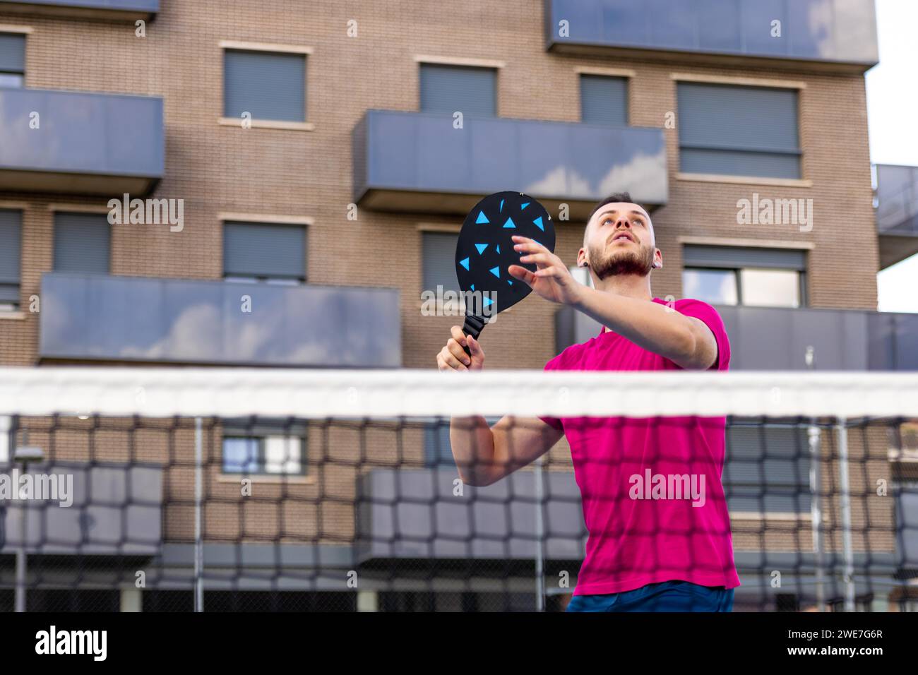 Uomo che si prepara a picchiare la palla in Pickleball. In Pickleball, è vietato il pallavolo (colpire la palla senza prima toccare il terreno) con qualsiasi Foto Stock