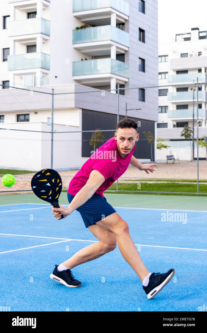 Uomo che gioca a picchettio, colpisce la palla da picchettio con pagaia, attività sportive all'aperto Foto Stock