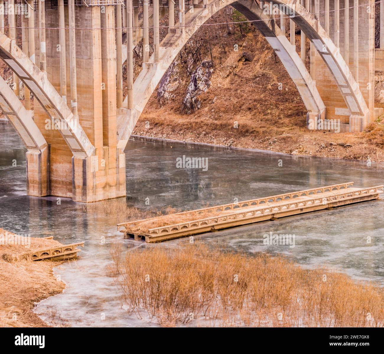 Ponte ad arco con colonne che si estendono su un fiume con un ponte più piccolo con pezzi mancanti in Corea del Sud Foto Stock