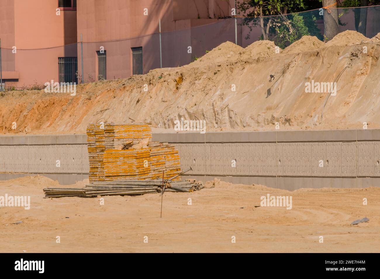 Forme di calcestruzzo e tubi per ponteggi in ferro impilati ordinatamente davanti a una parete in cemento presso il cantiere in Corea del Sud Foto Stock