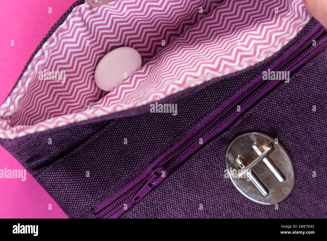 Un Apple Air Tag si trova in una pochette viola su uno sfondo rosa Foto Stock