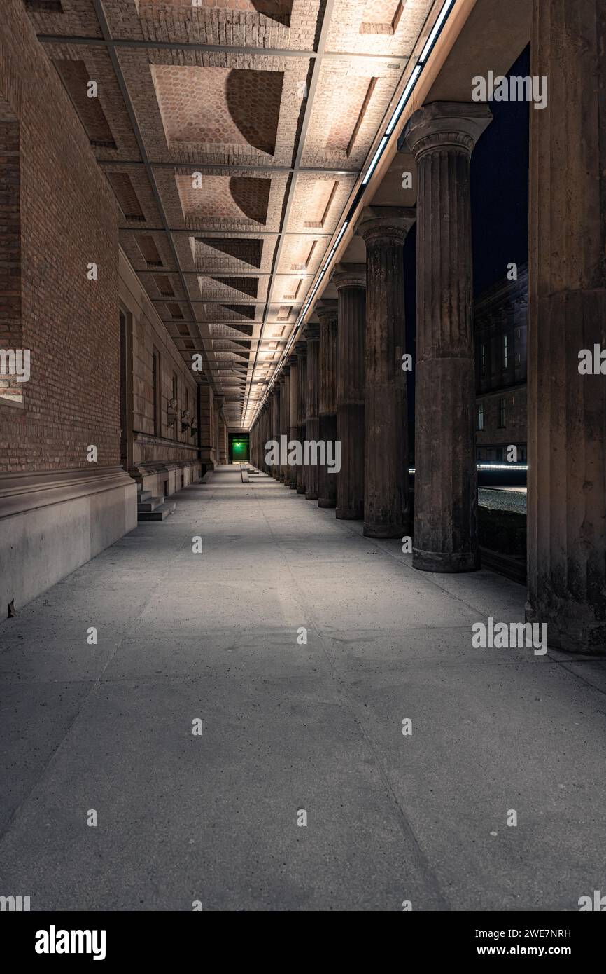 Vista notturna di un passaggio illuminato con colonne classiche e cielo scuro, Berlino, Germania Foto Stock