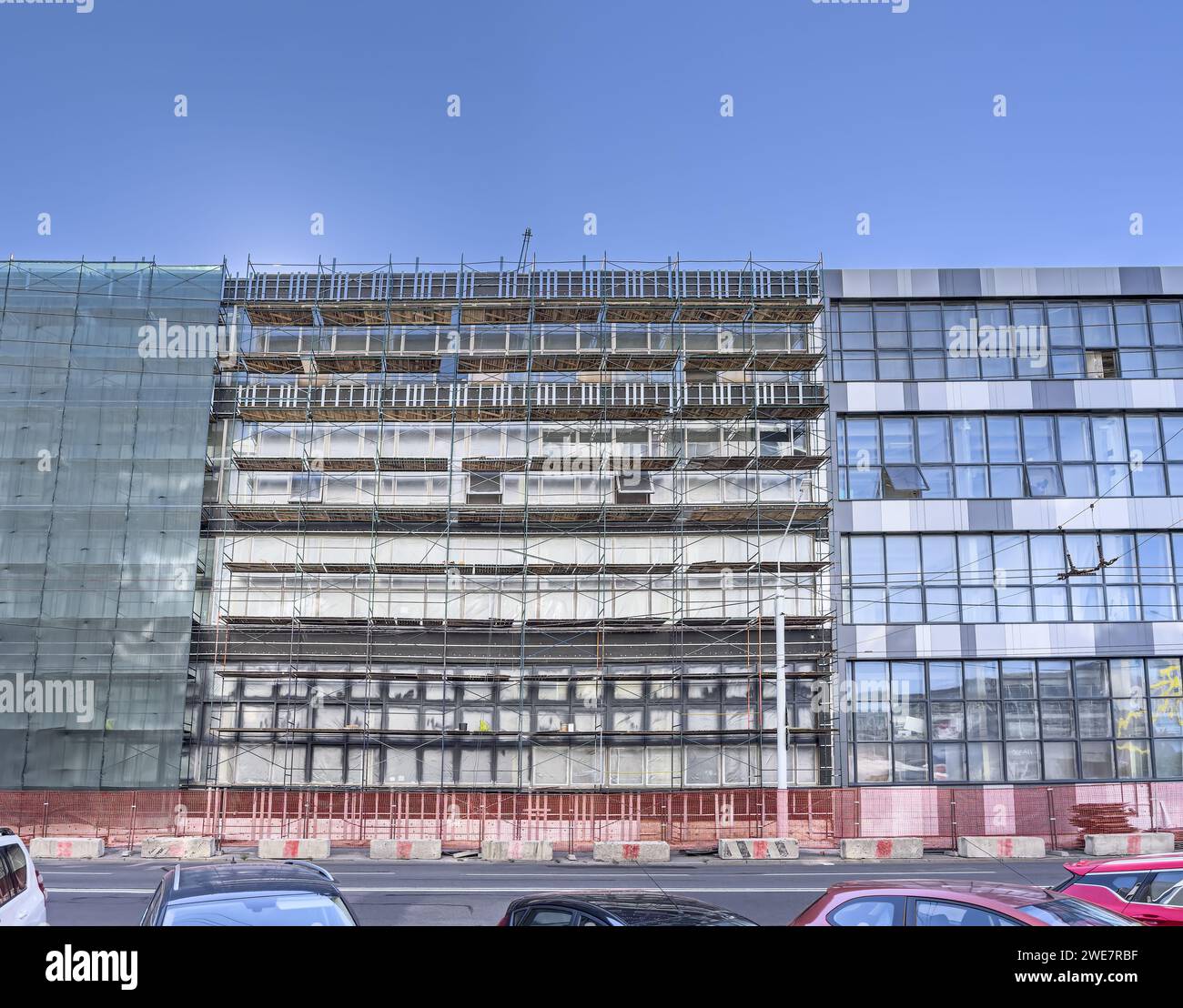 ristrutturazione della facciata di edifici industriali con ponteggi e reti di sicurezza. Foto Stock