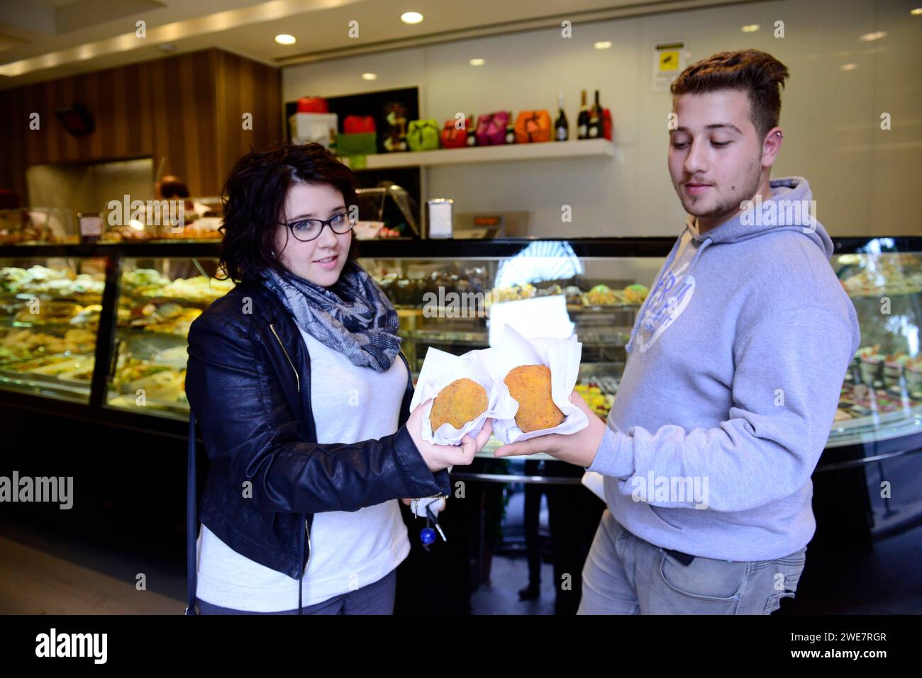 Una coppia italiana che mangia Aranchini al Bar Touring di Palermo, Sicilia, Italia. Foto Stock