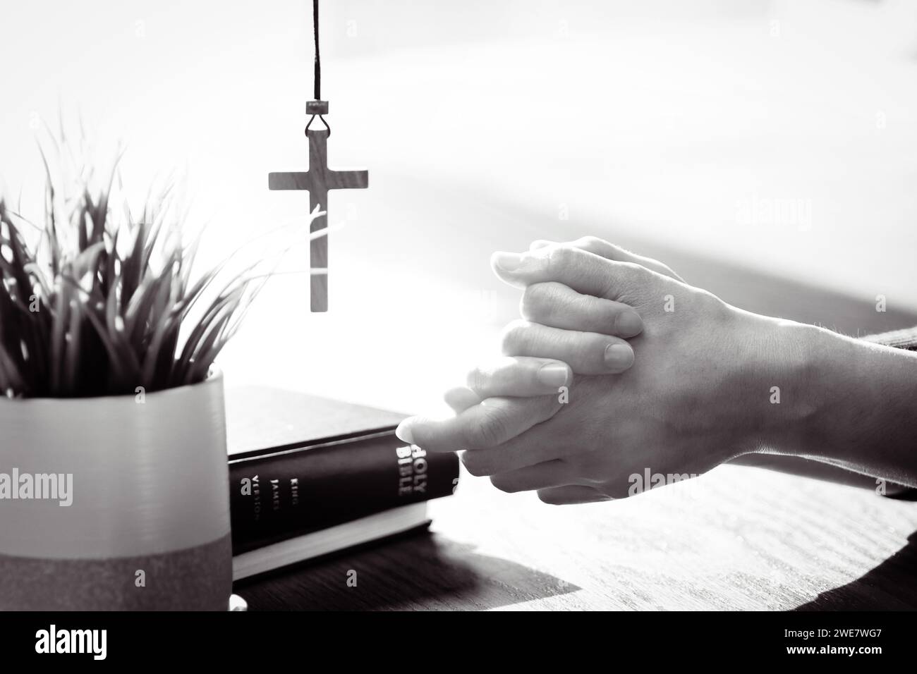Cristiani che pregano e adorano con le mani insieme, Bibbia luminosa e sfondo incrociato Foto Stock