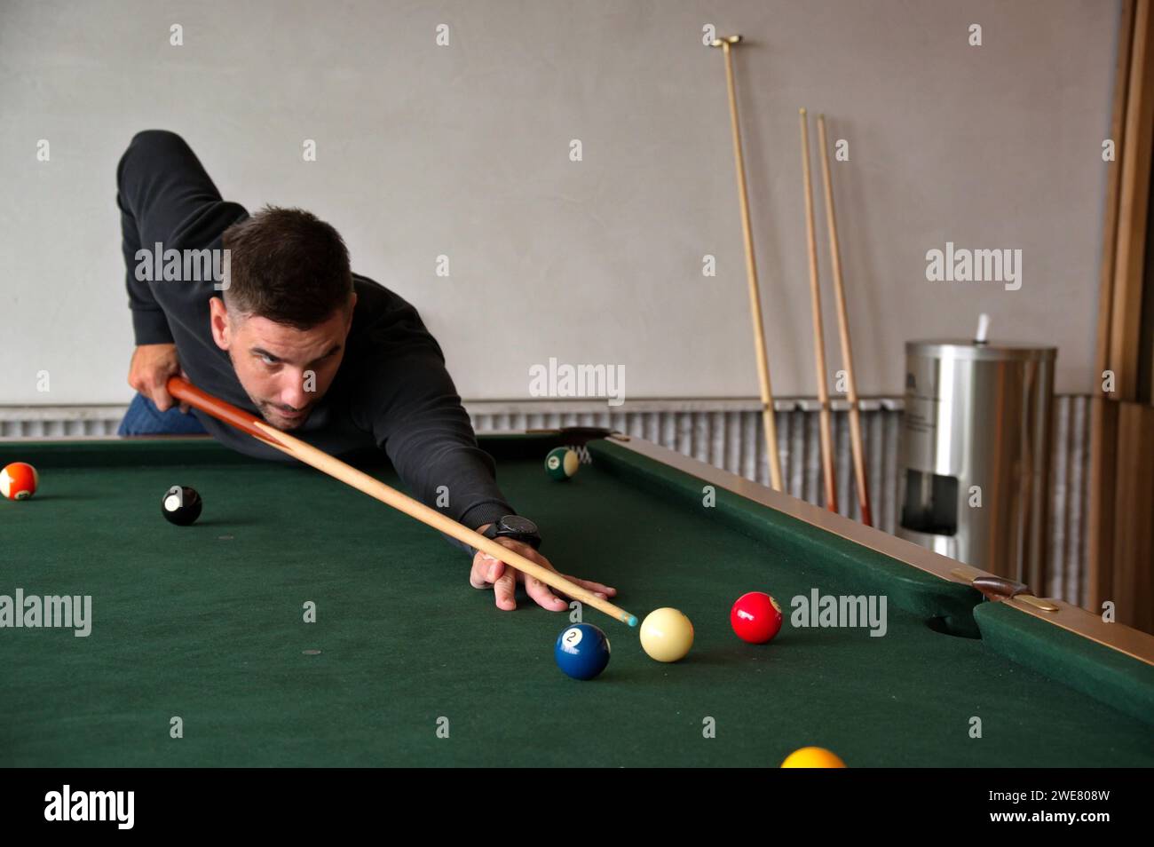 Uomo maturo che gioca a biliardo con l'obiettivo di sparare a palla Foto Stock