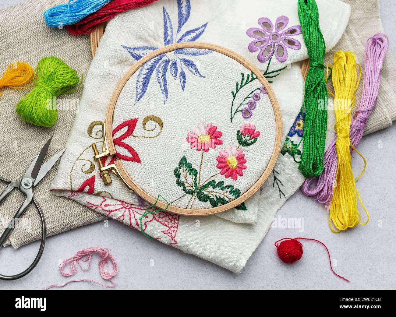 Processo di ricamo a mano un tovagliolo con fili colorati su tessuto bianco. Foto Stock