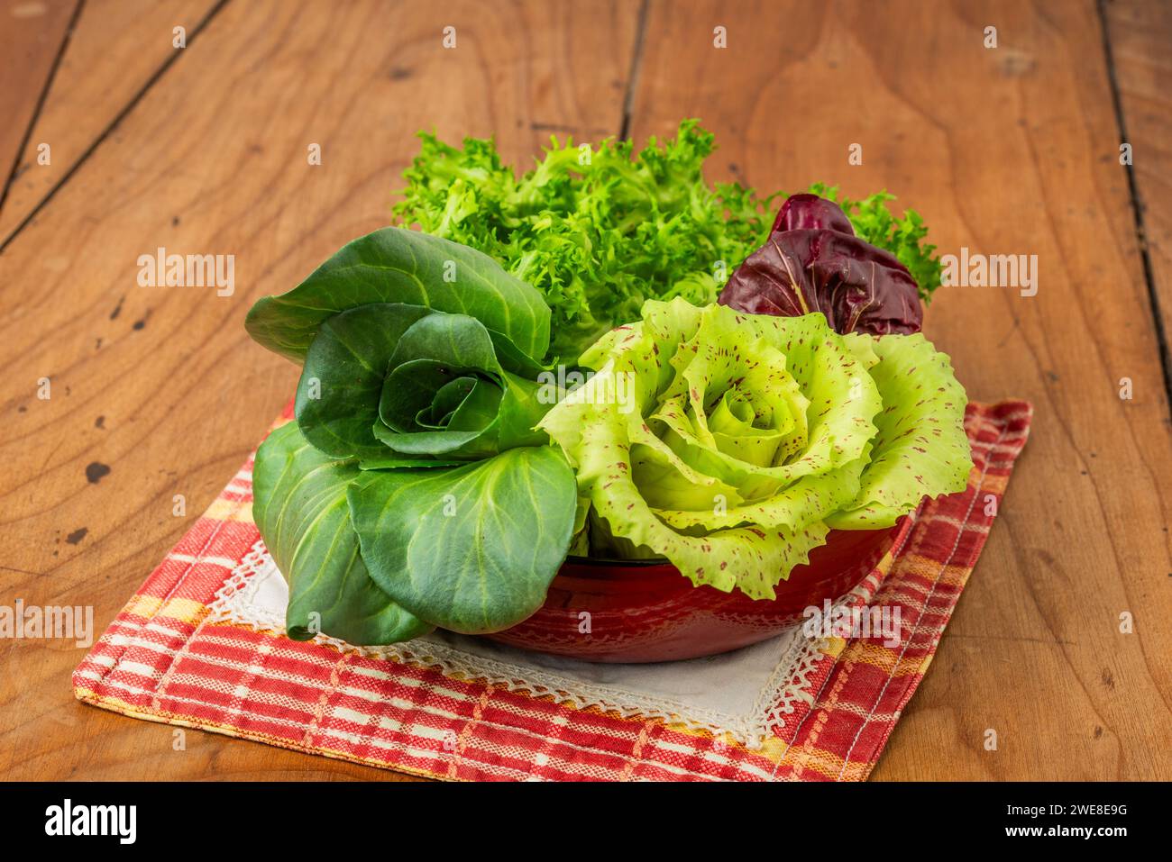 Quattro insalate in tazza su un antico tavolo in legno: Cicoria grumolo verde, radicchio di Chioggia, radicchio di Castelfranco e insalata riccia. Foto Stock