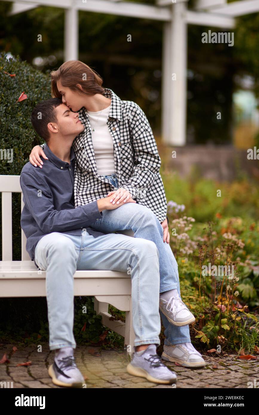 Romanticismo autunnale: Giovani coppie che si abbracciano e si baciano sulla panchina del parco. Giovani coppie che si baciano e si rallegrano al lago. adorabili giovani coppie che si baciano all'aperto Foto Stock