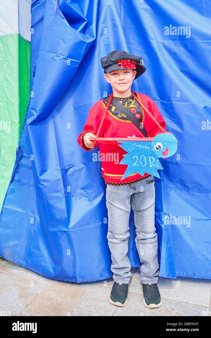 Giovane ragazzo in abiti nazionali russi. Peddler di piccoli oggetti sulla fiera tradizionale di Irbit, Russia. Foto Stock