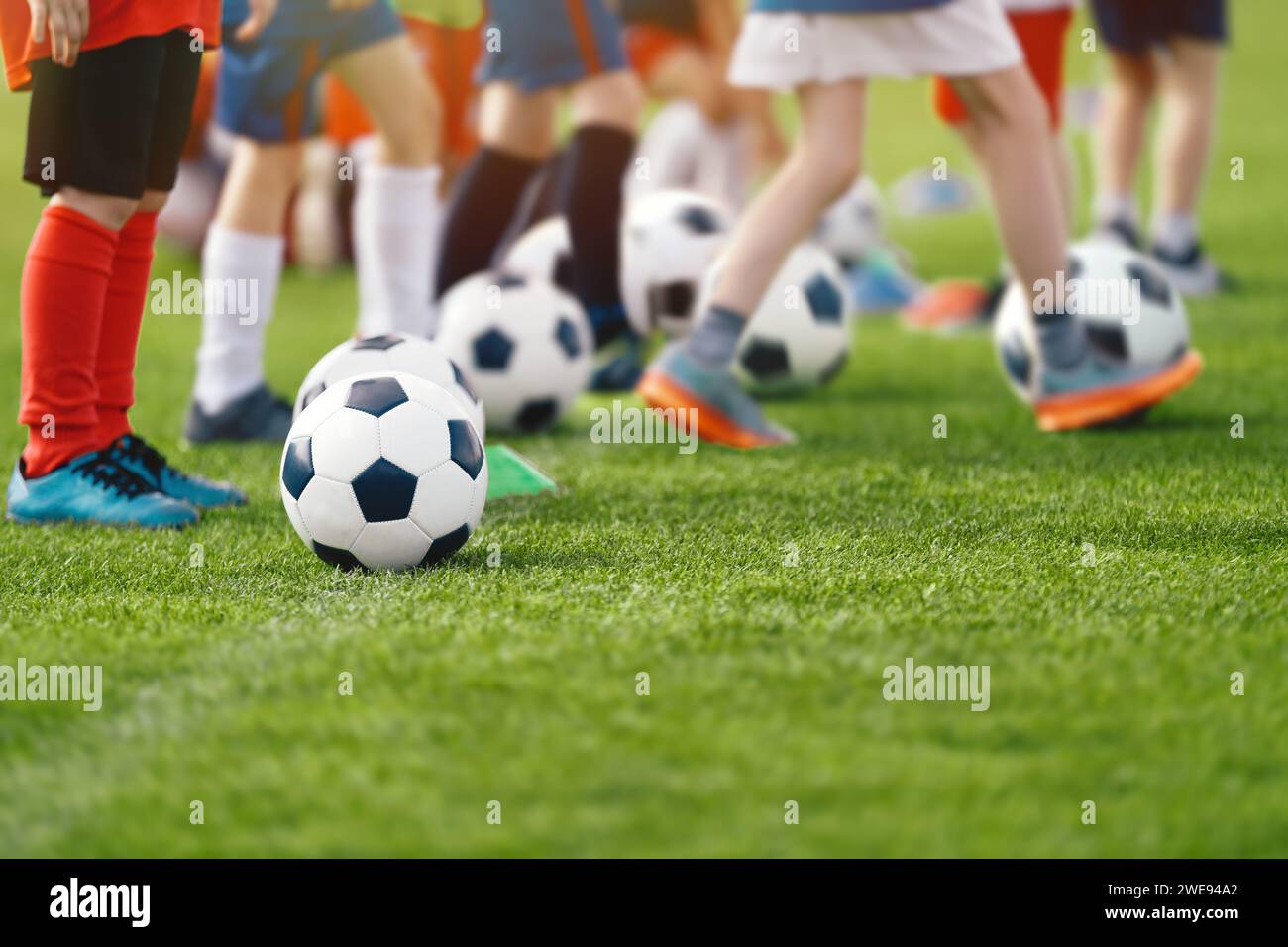 Lezione di calcio per bambini. Campo di allenamento di calcio. Bambini che praticano il calcio su un campo d'erba. Gruppo di bambini che corrono e calci Foto Stock