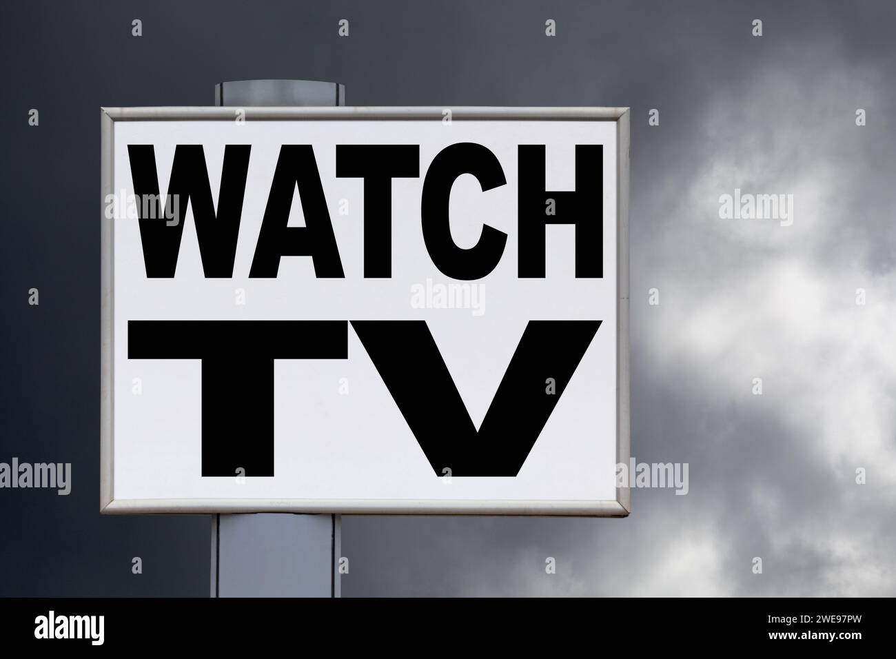 Primo piano su un cartellone bianco contro un cielo nuvoloso con il messaggio "Guarda la TV" scritto al centro. Foto Stock