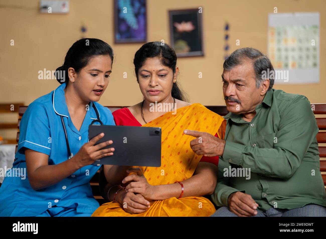 Infermiera indiana o caregiver a casa che spiega condizione medica alle coppie di mezza età - concetto di consulenza medica, occupazione professionale e Foto Stock