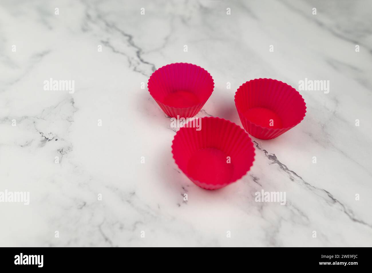 Vista dall'alto delle custodie per cupcake in silicone su sfondo in marmo bianco. Cottura di muffin e cupcake, stesa piatta, spazio per copiare. Foto Stock