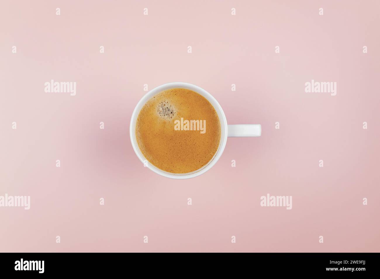 Vista dall'alto della tazza di caffè su sfondo rosa chiaro. Tazza bianca, base piatta, spazio copia. Foto Stock