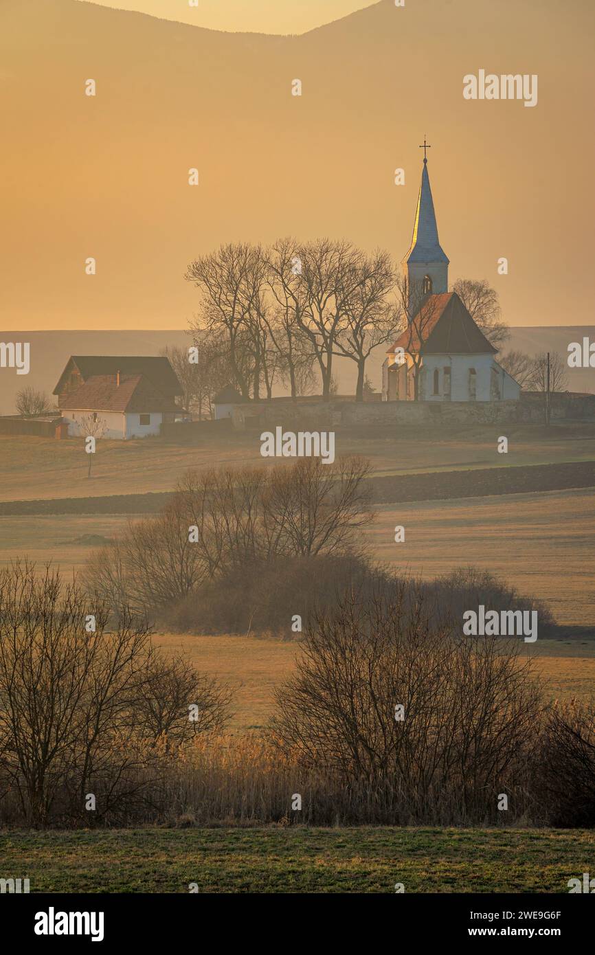 La vecchia chiesa di Delnita durante un tramonto spettacolare. Foto aerea scattata il 29 dicembre 2023 a Delnita, contea di Harghita, Transilvania, Romania. Foto Stock