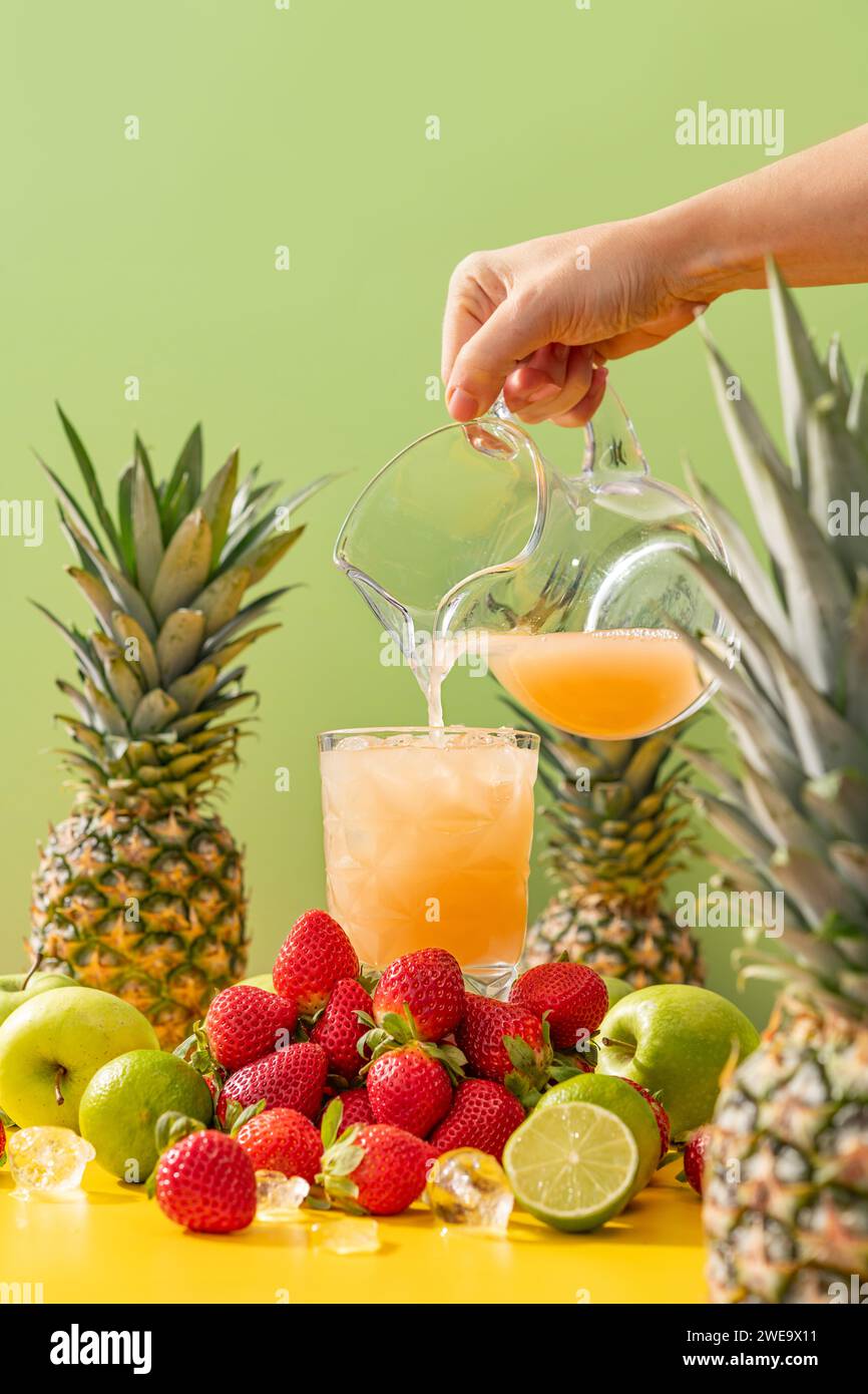 Succo fresco e freddo pieno di vitamine e sapori di ananas, mela, fragola e lime su fondo verde Foto Stock