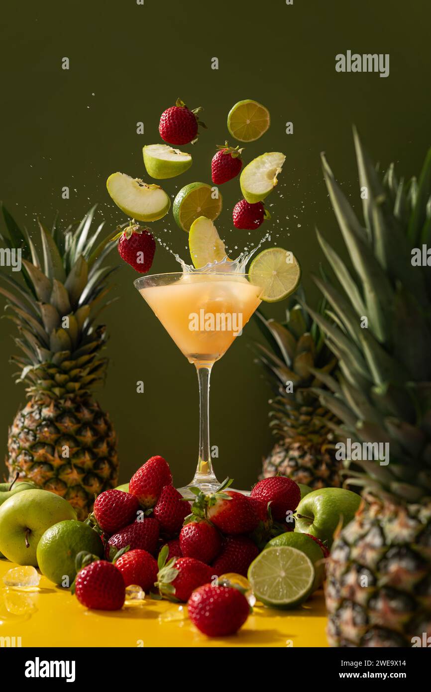 Succo fresco e freddo pieno di vitamine e sapori di ananas, mela, fragola e lime su fondo verde Foto Stock