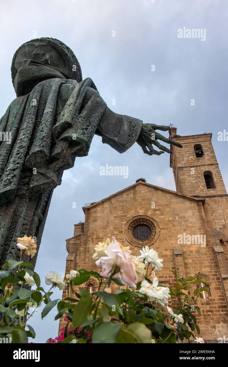 EN Alcántara, imagen desde atrás de la estatua de bronce de San Pedro de Alcántara como tocando con su mano la torre de la iglesia, Cáceres, España Foto Stock