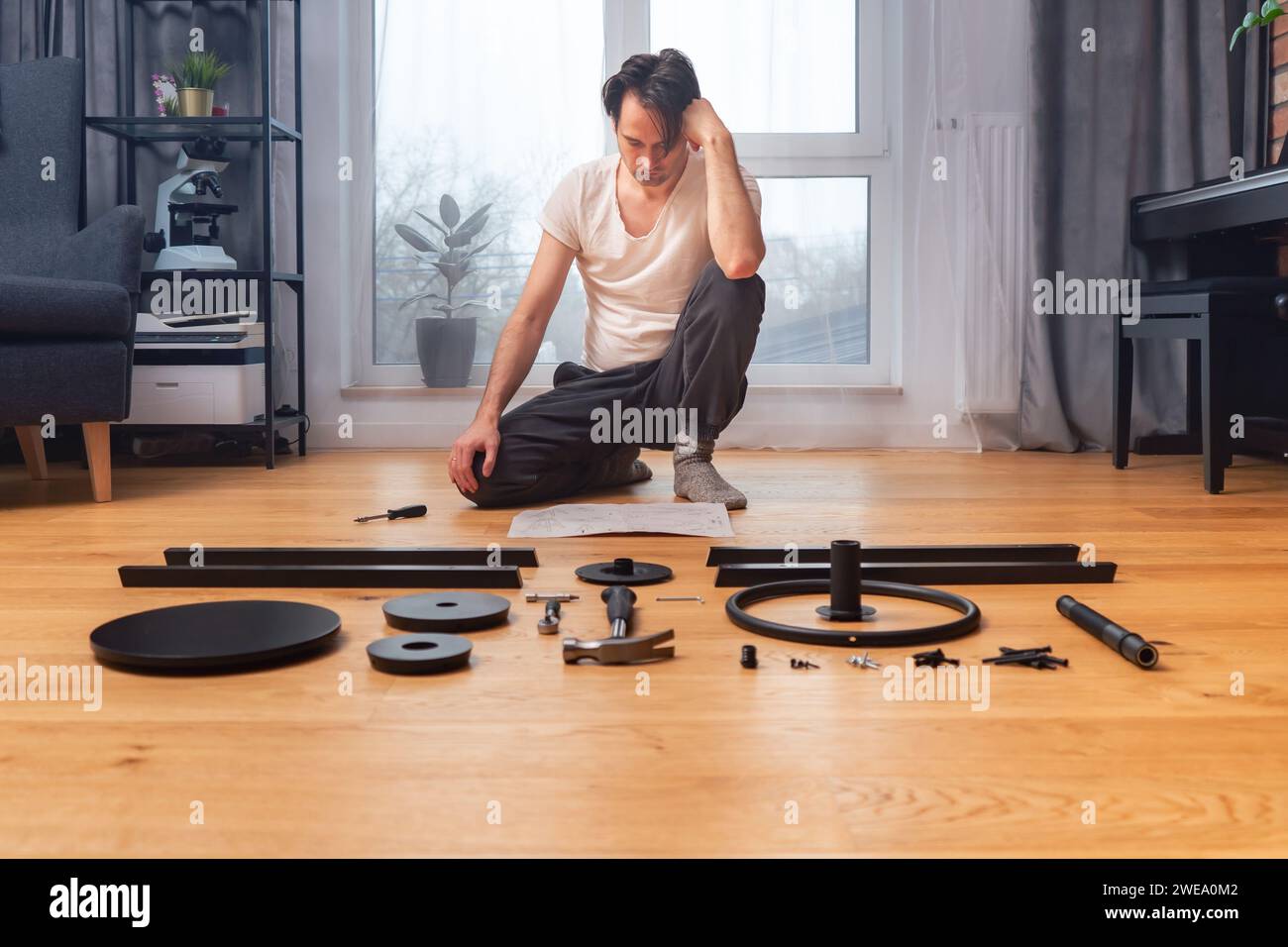 L'uomo sta cercando di capire le istruzioni per l'auto-assemblaggio dei mobili. Foto Stock