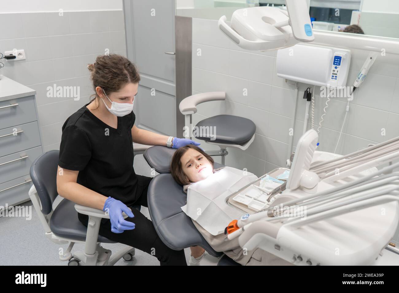 Un dentista pediatrico esamina un bambino ansioso che è venuto a un appuntamento per la prima volta. Visita medica di un bambino presso un dentista pediatrico Foto Stock