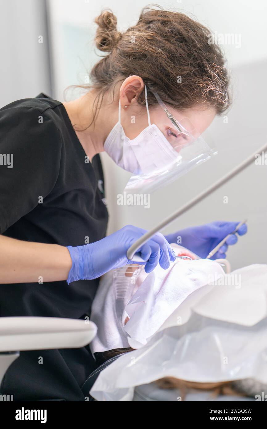 Una dentista femminile fornisce cure dentali di emergenza a un paziente in una clinica dentale. Foto Stock