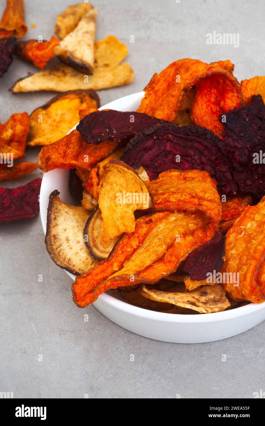 Patatine a base di verdure a radice. Carote, barbabietole e patate dolci. Su una superficie grigia a chiazze con spazio di copia Foto Stock Patatine a base di verdure a radice. Carote, barbabietole e patate dolci. Su una superficie grigia a chiazze con spazio di copia Foto Stock