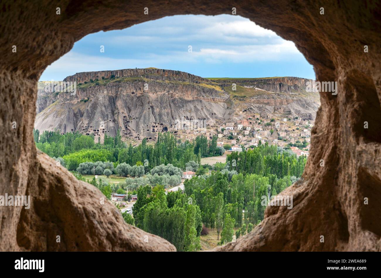 Vista di una valle lussureggiante e formazioni rocciose da una grotta che si apre come una finestra rotonda, che mostra la natura e la geologia, in Cappadocia, Turchia Foto Stock