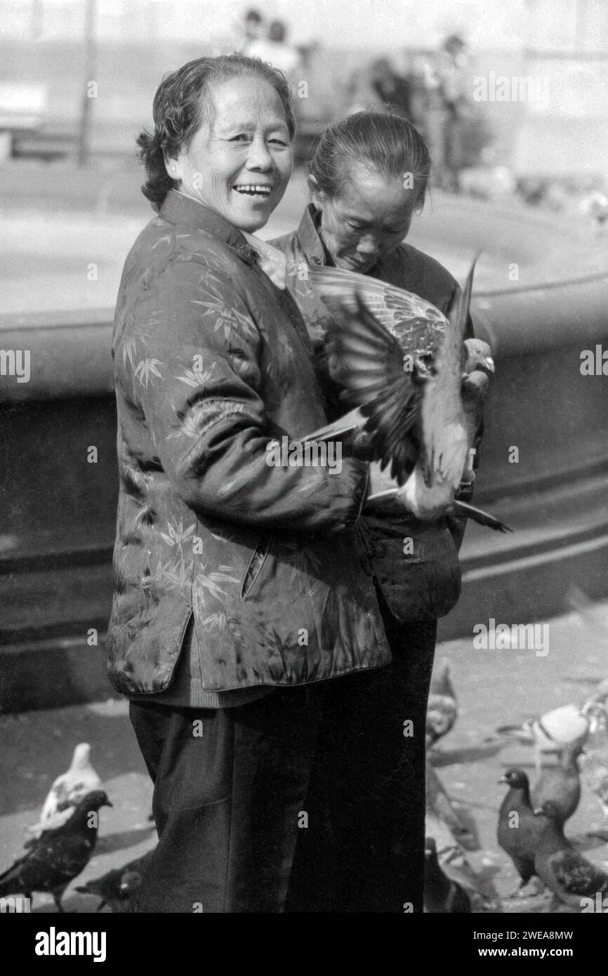 Due donne cinesi che nutrono i piccioni a Trafalgar Square, Londra, intorno al 1979 Foto Stock