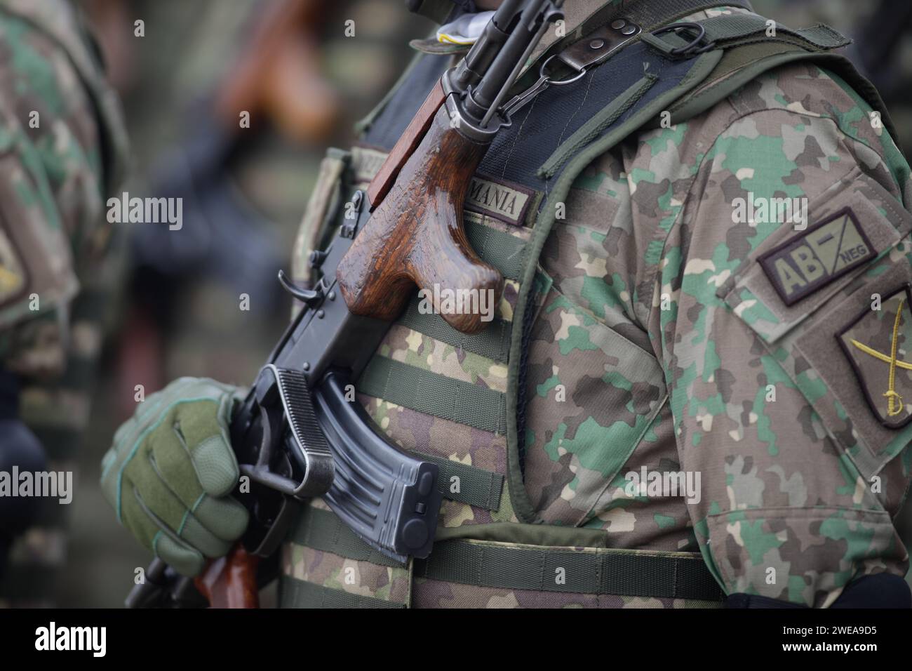 Bucarest, Romania - 24 gennaio 2024: Dettagli con un soldato dell'esercito rumeno in possesso di un fucile d'assalto AK 47 durante una cerimonia militare presso il monumento Foto Stock