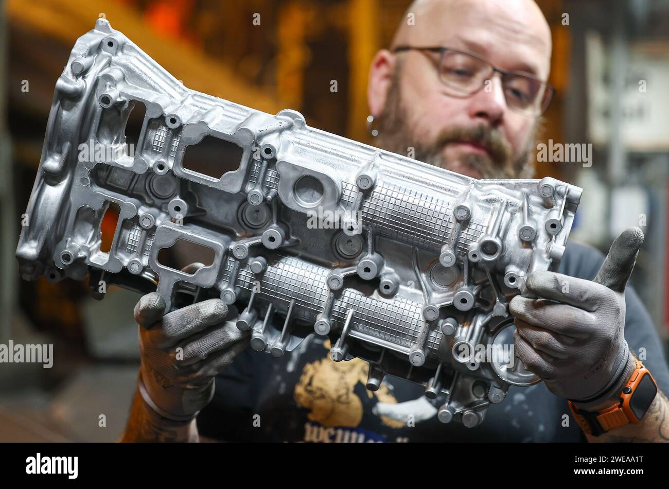 Annaberg Buchholz, Germania. 24 gennaio 2024. Un dipendente della Handtmann Leichtmetallgießerei Annaberg GmbH ispeziona una fusione di alluminio dopo la fusione. 328 dipendenti producono ben 60.000 tonnellate di pezzi fusi speciali nello stabilimento delle montagne minerali, principalmente per l'industria automobilistica. Fondata nel 1926 come fonderia DKW, le parti per le motociclette MZ sono state prodotte qui durante l'era della DDR. Dopo la riunificazione, la società è stata rilevata dal gruppo Handtmann di società di Biberach e ulteriormente ampliata. Crediti: Jan Woitas/dpa/Alamy Live News Foto Stock