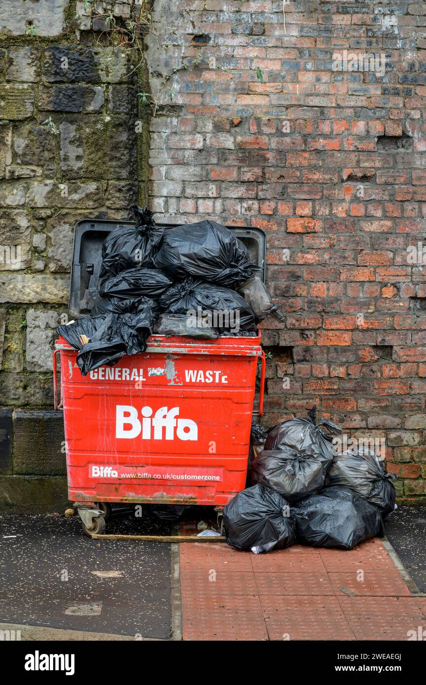 Un contenitore per rifiuti biffa pieno pieno pieno riempito con rifiuti commerciali generici in sacchi neri, Glasgow, Scozia, Regno Unito, Europa Foto Stock