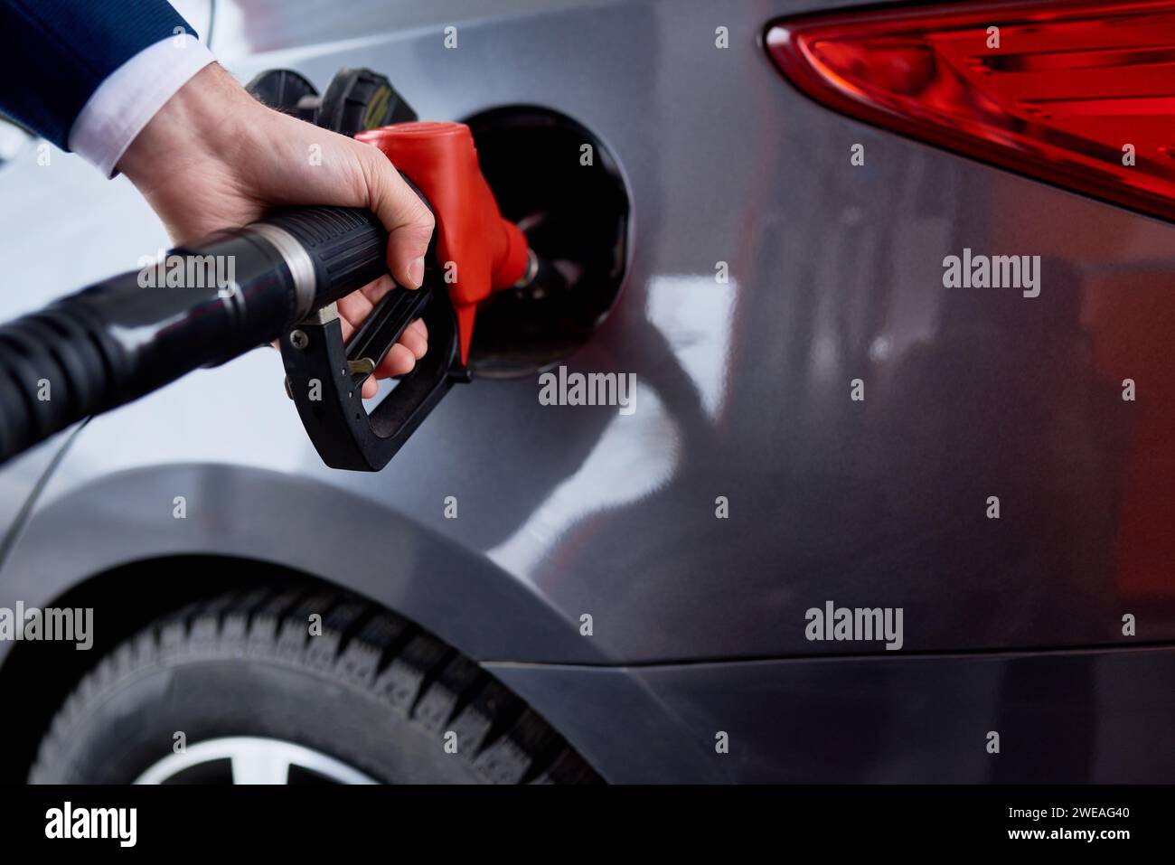 Primo piano del serbatoio di benzina di rifornimento a mano maschile di un'auto di lusso nera presso la stazione di servizio, spazio fotocopie Foto Stock