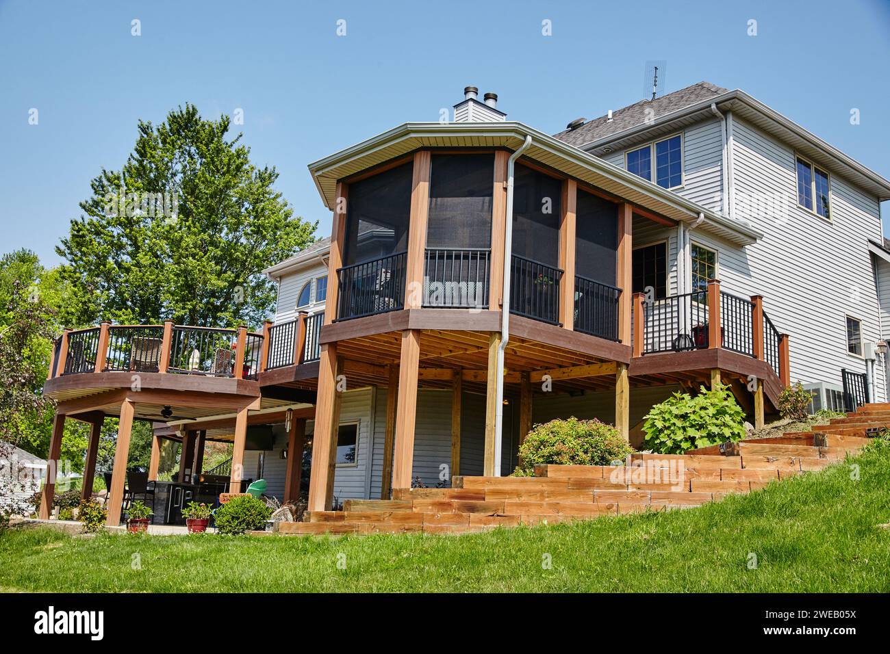 Terrazza suburbana in legno con portico schermato e cortile lussureggiante Foto Stock
