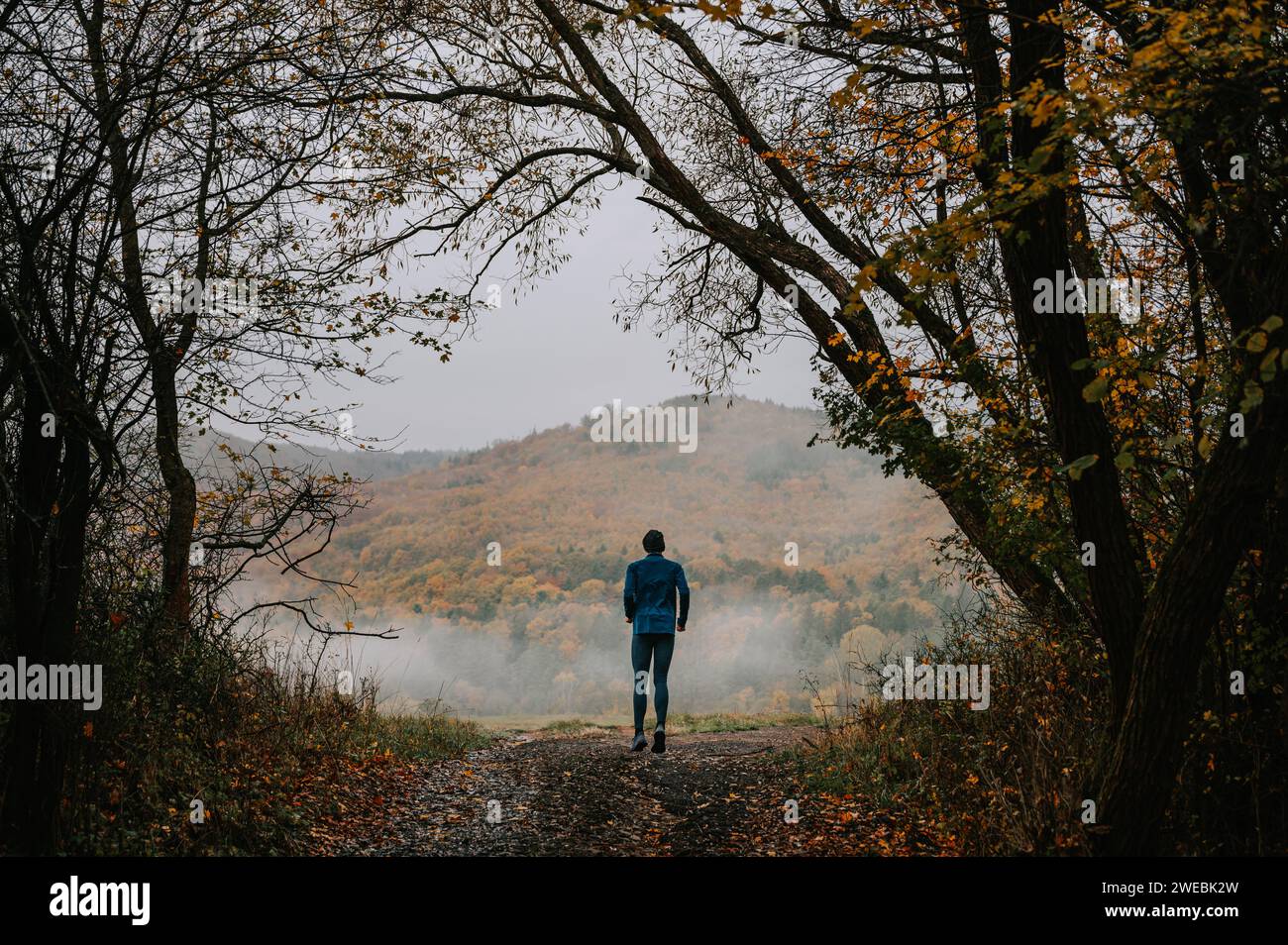Passi silenziosi in autunno: Il viaggio di un giovane corridore alla tranquillità Foto Stock