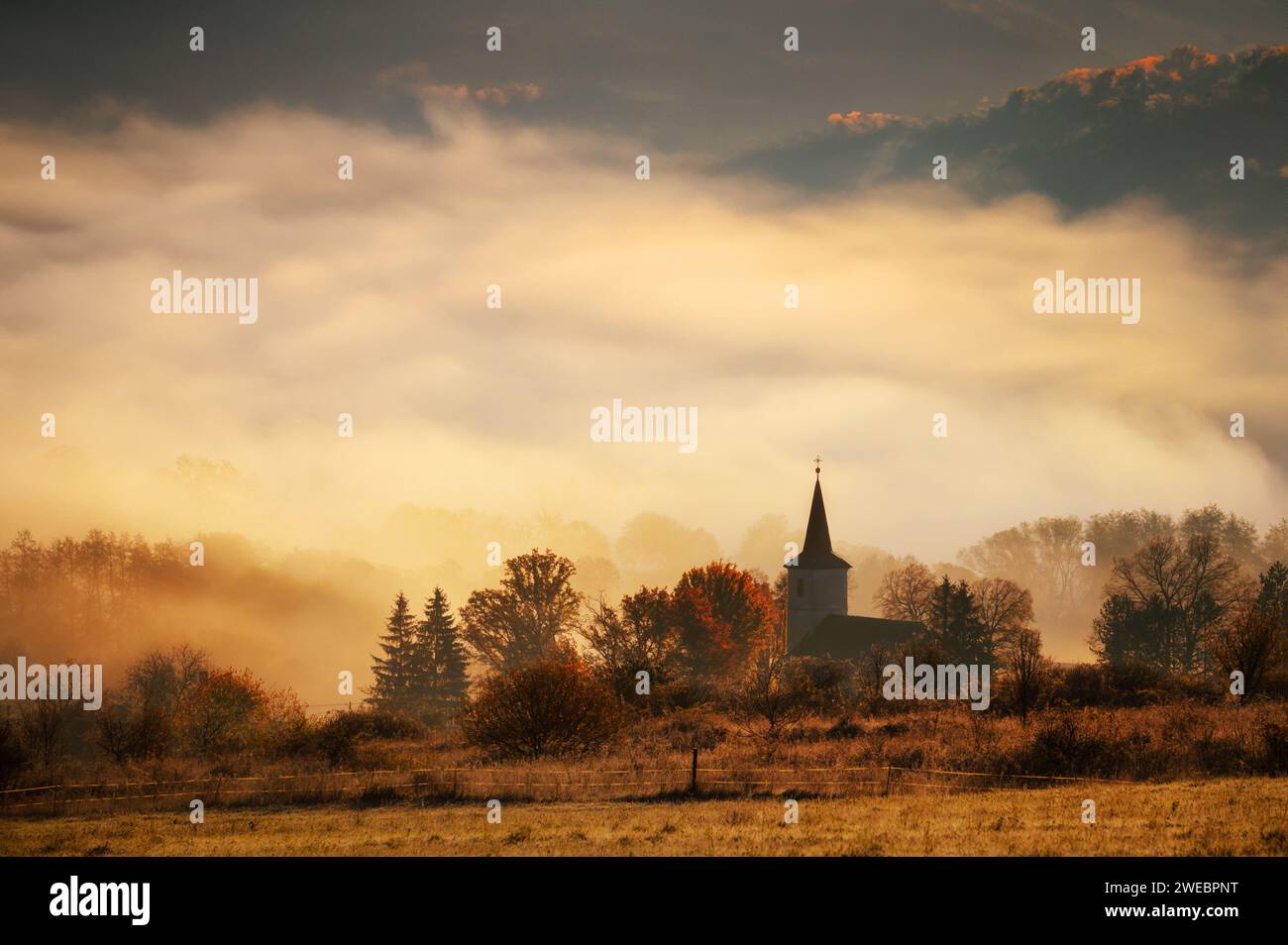 Immagine con il motivo della fede cristiana, la sagoma della chiesa cristiana, il sole mattutino e la nebbia sullo sfondo. Estate indiana, o Foto Stock Immagine con il motivo della fede cristiana, la sagoma della chiesa cristiana, il sole mattutino e la nebbia sullo sfondo. Estate indiana, o Foto Stock