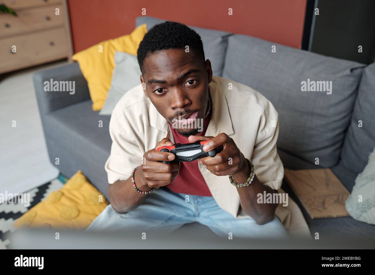 Teso uomo afroamericano con gamepad nelle mani che guarda lo schermo del computer durante il videogioco e guarda i personaggi dopo Foto Stock