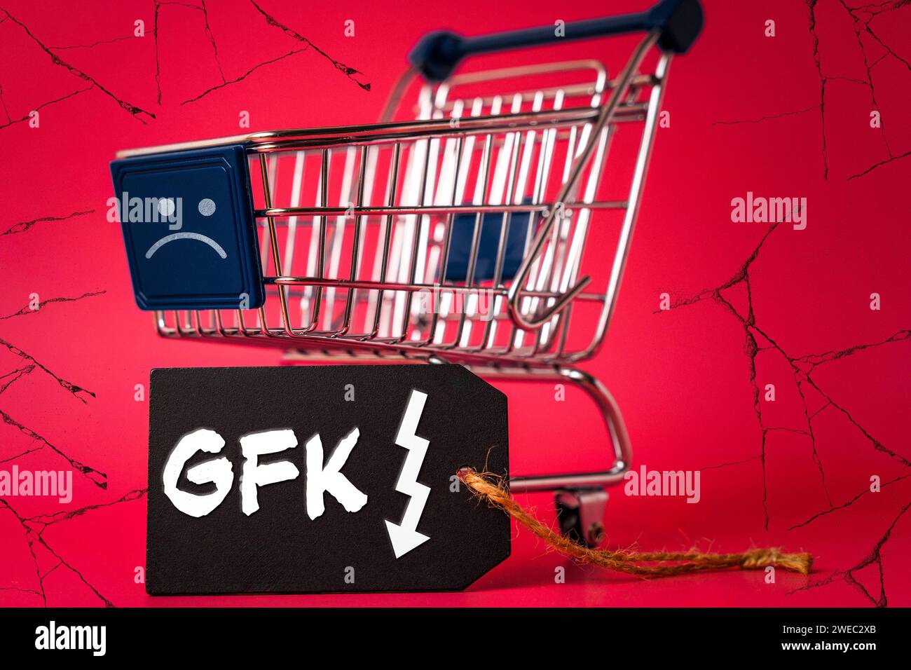 24 gennaio 2024: Carrello della spesa con un sorriso triste, sfondo sgretolante e un'etichetta con la scritta: GFK consumer climate index shows negative consumer sentiment FOTOMONTAGE *** Einkaufswagen mit einem traurigen Smiley, bröckelnden Hintergrund und einem Etikett mit Aufschrift: GFK Konsumklimaindex zeigt negative Verbrauchermung FOTOMONTAGE Foto Stock