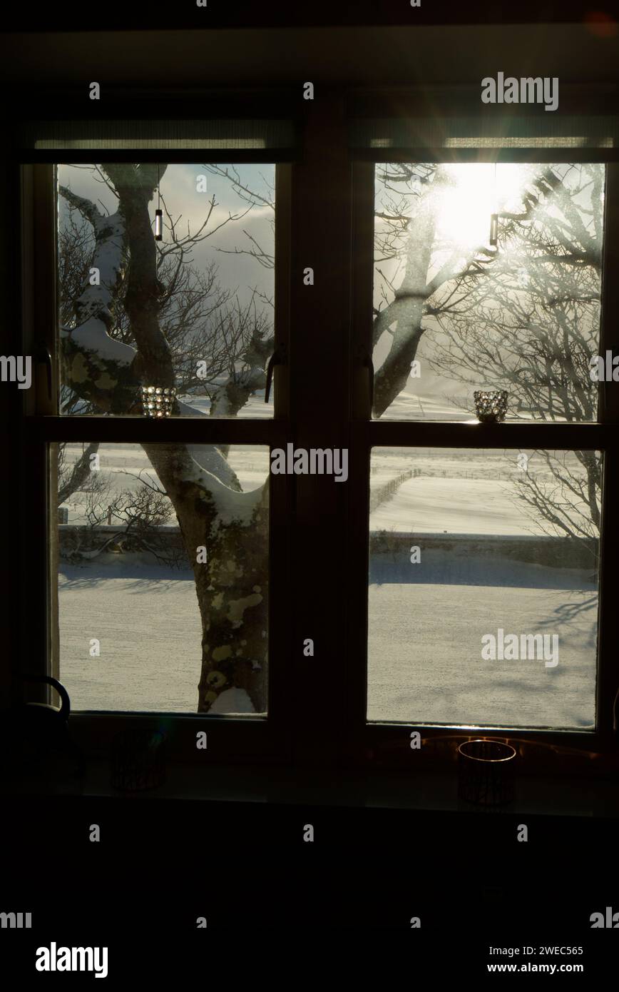 La luce del sole invernale splende attraverso la finestra del cottage Foto Stock