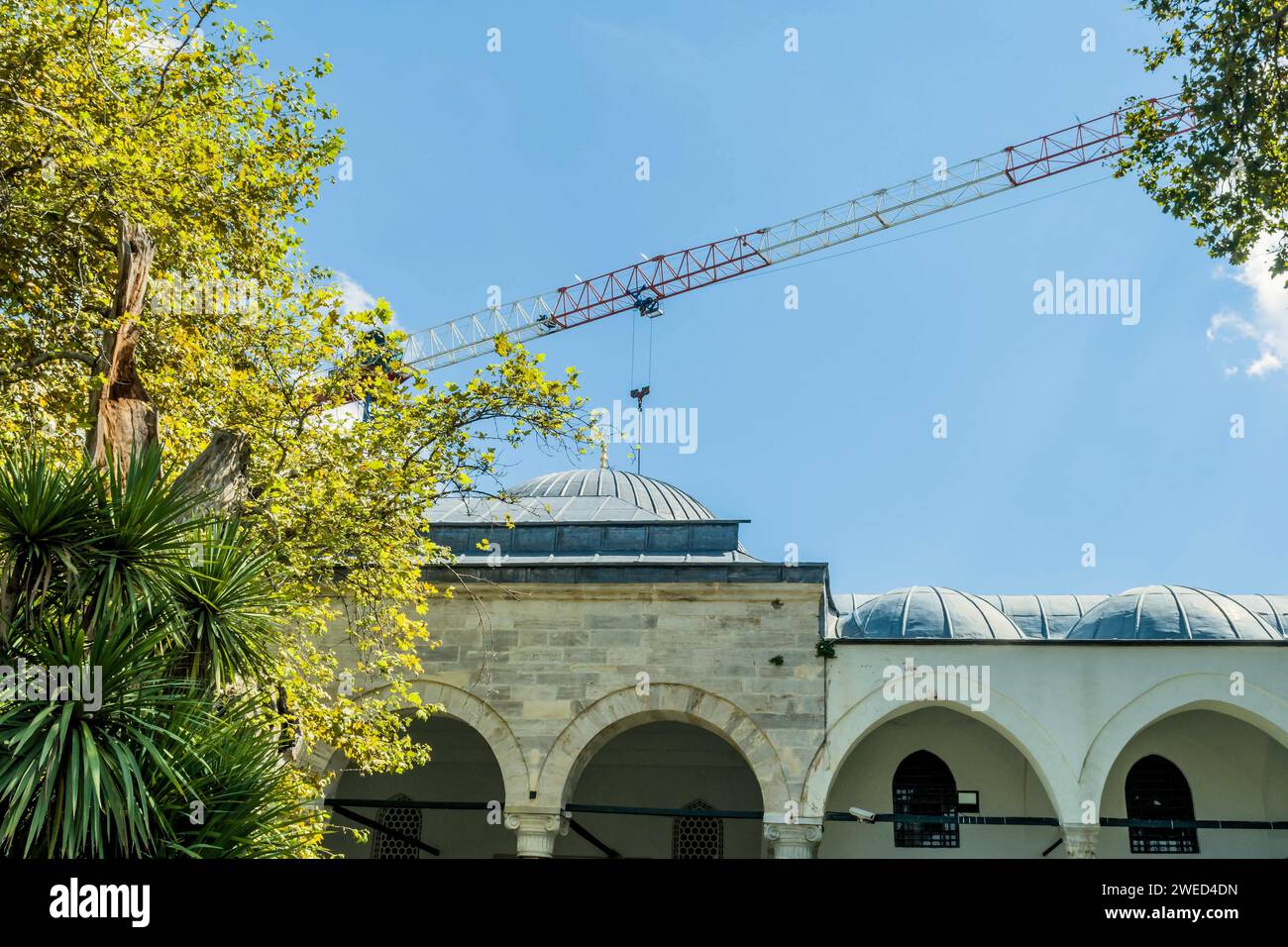 Braccio gru sopra le cupole della moschea contro il cielo blu a Istanbul, Turkiye Foto Stock