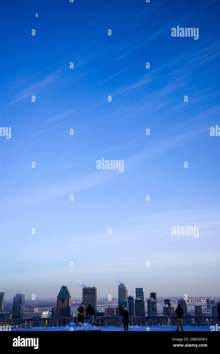 Lo skyline della città è formato dalle sagome di grattacieli contro un cielo blu, i venti invernali intrecciano delicatamente nuvole bianche Foto Stock