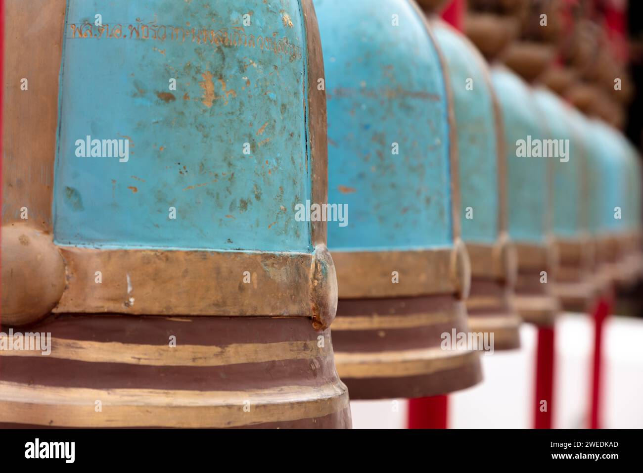 Vista ravvicinata, campane religiose a Wat Rakhang a Bangkok, Thailandia. Campane color rame e turchese con iscrizione. Foto Stock