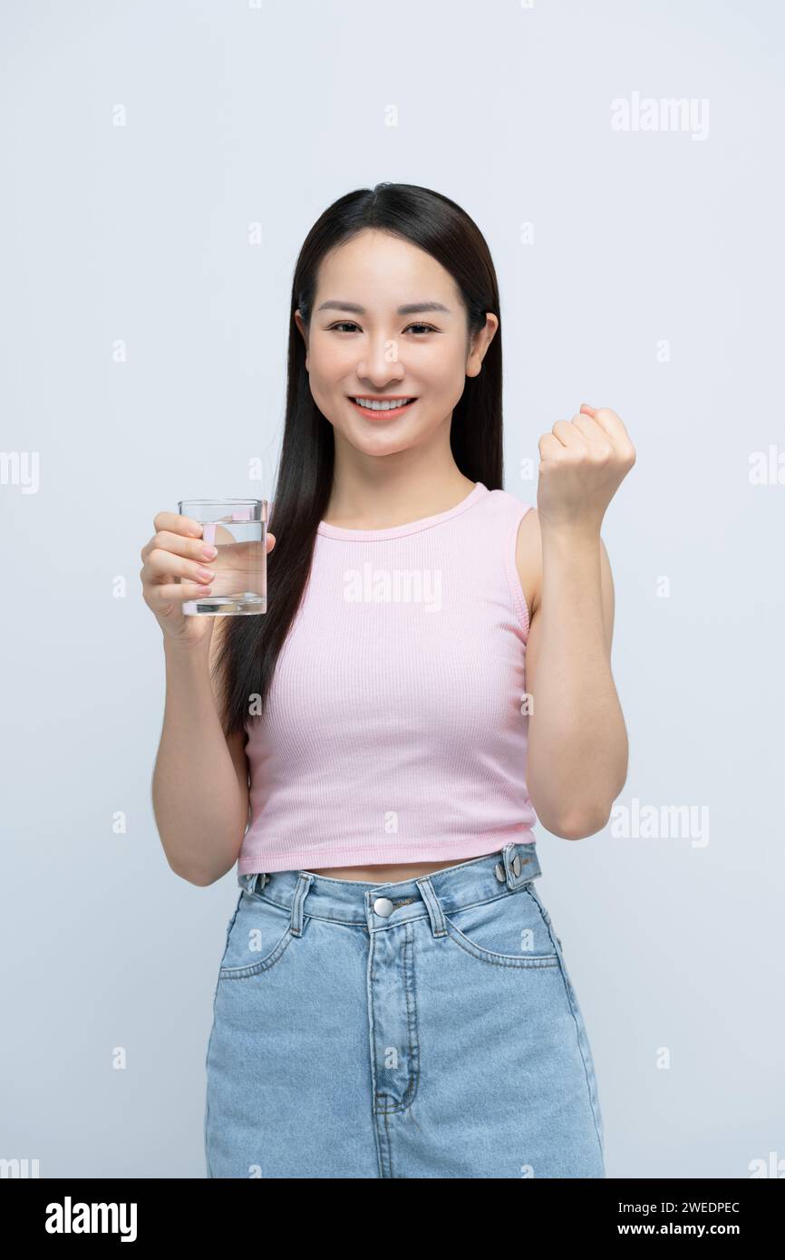 Donna asiatica che beve un bicchiere d'acqua che urla orgogliosa, festeggia la vittoria con il braccio sollevato Foto Stock