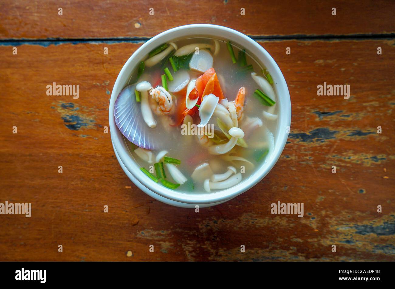 Vista dall'alto del pesce Tom Yum Kung su un tavolo di legno. Zuppa thailandese piccante e limpida con gamberi e frutti di mare. Cibo asiatico. Gamberi in zuppa piccante, Tom y Foto Stock