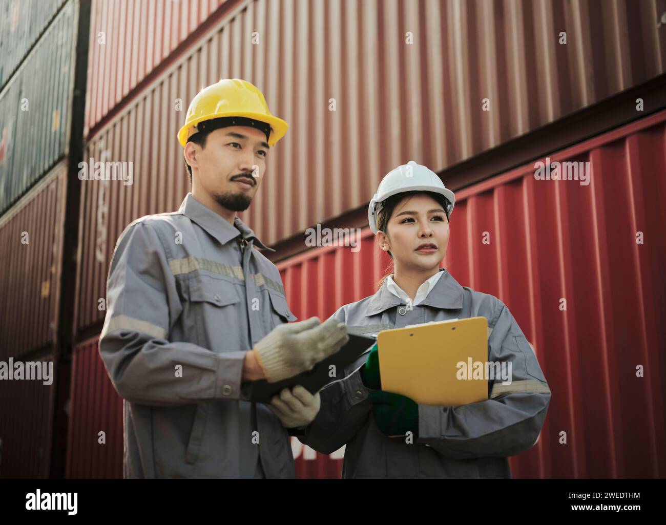 Il team di ingegneri discute dei problemi e prende nota ascoltando il manager che condivide un'idea sul lavoro nell'area del container cargo Foto Stock