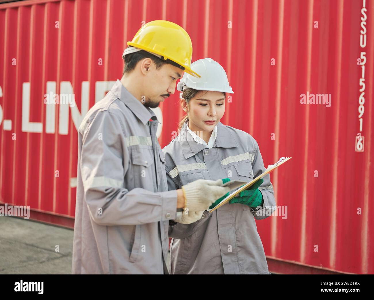 Il team di ingegneri discute dei problemi e prende nota ascoltando il manager che condivide un'idea sul lavoro nell'area del container cargo Foto Stock