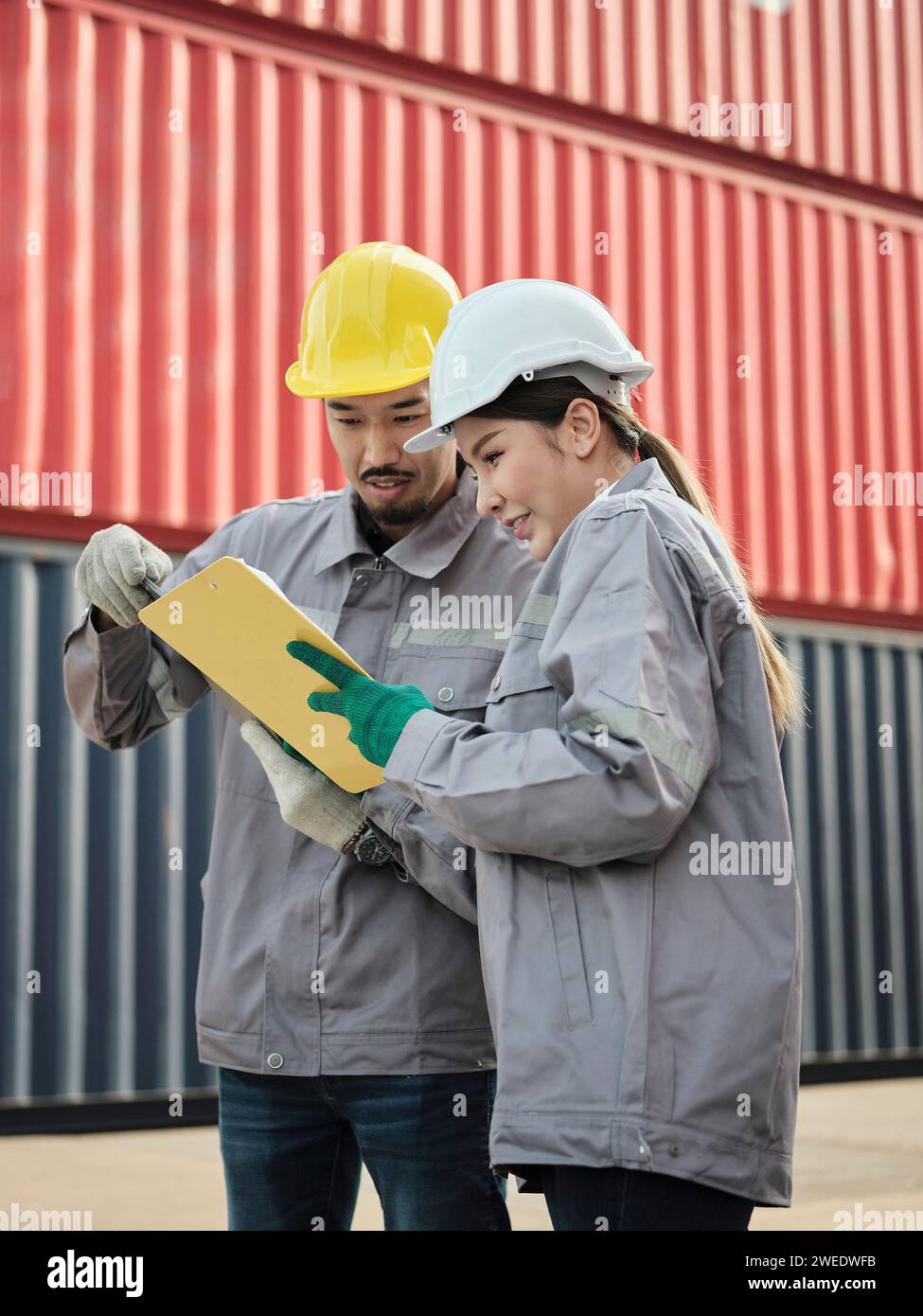 Il team di ingegneri discute dei problemi e prende nota ascoltando il manager che condivide un'idea sul lavoro nell'area del container cargo Foto Stock