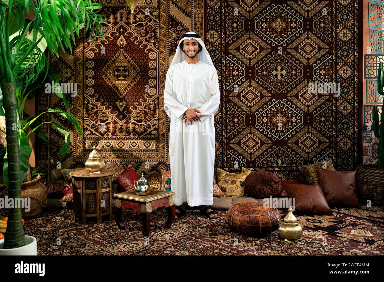 Uomo degli emirati che indossa un abito kandura trascorre del tempo in una casa tradizionale araba a Dubai Foto Stock