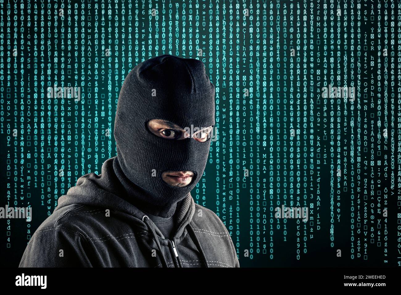 Criminale che indossa balaclava nera e felpa con cappuccio su sfondo blu di codice informatico Foto Stock