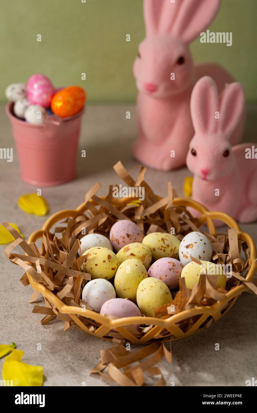 Uova di caramelle al cioccolato pasquale nel cestino e coniglio rosa Foto Stock